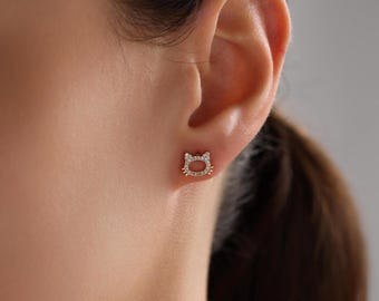May include: A pair of gold cat-shaped stud earrings with clear cubic zirconia stones.
