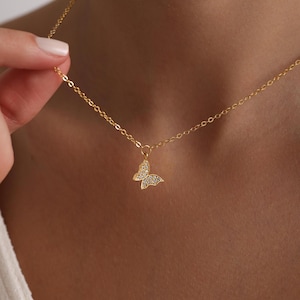 May include: A gold chain necklace with a small, sparkly butterfly pendant.