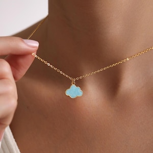Puede incluir: Un collar de cadena dorada con un colgante de nube azul claro.