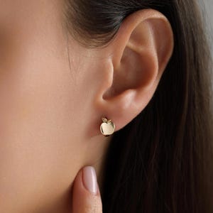 Puede incluir: Pendientes de botón de oro en forma de manzana con un pequeño detalle de hoja.