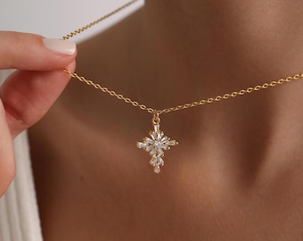 May include: A gold chain necklace with a small, sparkly cross pendant. The cross is made of clear cubic zirconia stones.
