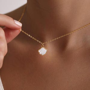 May include: A gold chain necklace with a white seashell pendant.