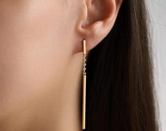 May include: Gold bar earrings with a row of small clear stones.
