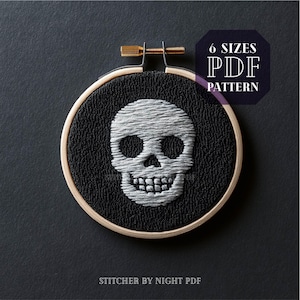 Puede incluir: Un cráneo blanco bordado sobre tela negra en un aro de bordado de madera. El texto "6 SIZES PDF PATTERN" está en la esquina superior derecha de la imagen. El texto "STITCHER BY NIGHT PDF" está en la parte inferior de la imagen.