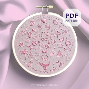 Può includere: Un telaio da ricamo rosa con tessuto rosa chiaro con disegni ricamati a tema estivo in filo rosa. I disegni includono un sole, conchiglie, palme e le parole "Summer vibe". Un'etichetta bianca con motivo PDF si trova in alto a destra.