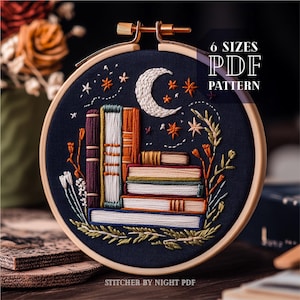 May include: Embroidered hoop art with a dark blue background, depicting a stack of books, a crescent moon, and stars. The text reads "6 SIZES PDF PATTERN". The embroidery uses white, orange, brown, and green threads.