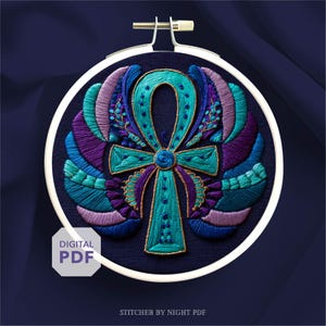 May include: An embroidered Ankh symbol in a white hoop. The Ankh is teal, blue, purple, and gold, with a detailed wing design. The words "DIGITAL PDF" are in a white box. The background is a dark blue fabric.
