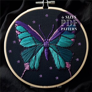 May include: Embroidered butterfly design on black fabric in a wooden embroidery hoop. The butterfly is teal, purple, and pink with a dark background and purple stars. The text "6 SIZES PDF PATTERN" is in white on a black rectangle.