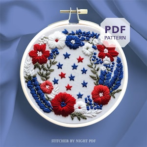 May include: Embroidered hoop art with a patriotic theme, showcasing red, white, and blue flowers and stars. The embroidery is set against a white fabric, held within a wooden hoop. The text "PDF PATTERN" is visible.
