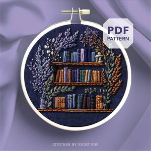 Könnte beinhalten: Gesticktes Hoop-Art mit einem Bücherregal-Design mit bunten Büchern und floralen Akzenten. Das Kunstwerk ist vor einem dunkelblauen Hintergrund platziert und enthält den Text "PDF PATTERN". Der Text "Stitcher by Night PDF" ist ebenfalls sichtbar.