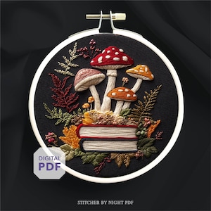 Puede incluir: Bordado en bastidor con diseño de setas rojas, naranjas y marrones sobre una pila de libros. El diseño incluye detalles de hojas bordadas sobre un fondo negro. Las palabras "DIGITAL PDF" son visibles. El conjunto está en un aro blanco.