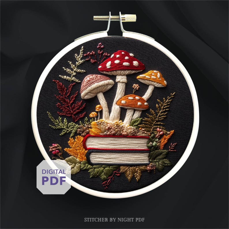 May include: Embroidered hoop art with a mushroom design in red, orange, and brown, on a stack of books. The design includes detailed stitching of foliage and the text "DIGITAL PDF". The hoop is approximately 15 cm in diameter.