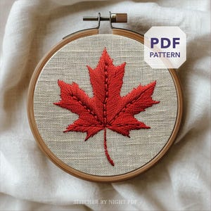 May include: A red embroidered maple leaf on beige fabric, framed by a wooden embroidery hoop. The text "PDF PATTERN" is displayed on the upper right. The image is set against a white fabric background.