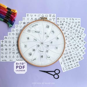 May include: An embroidery hoop calendar with a light fabric, displaying the months of "January" and "March". It includes icon stickers, embroidery floss, and black scissors. The calendar is labelled "8+10" PDF CALENDAR".