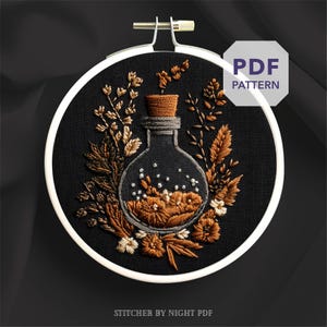 May include: An embroidered design of a glass bottle with a cork stopper, filled with flowers and surrounded by foliage in brown and cream hues, set against a black backdrop. The text "PDF PATTERN" is visible. The text "STITCHER BY NIGHT PDF" is also visible.