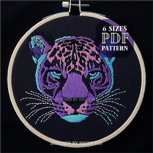 May include: Embroidery pattern for a purple and pink jaguar head with blue accents. The pattern is available in 6 sizes and is a PDF download. The text "6 SIZES PDF PATTERN" is in white on a black background.