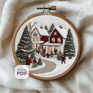 May include: Embroidered winter scene in a wooden hoop. The artwork depicts snow-covered houses, evergreen trees, and figures walking on a snowy path. The houses are red and white, with lit windows. The text "DIGITAL PDF" is visible.