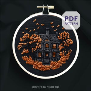 Peut inclure: Un cercle de broderie représentant une maison hantée. La maison est grise foncée avec des fenêtres orange, entourée d'arbres et d'oiseaux orange, le tout brodé sur un tissu noir. Le texte "PDF PATTERN" est visible.