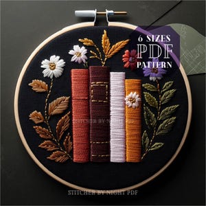Può includere: Un cerchio da ricamo nero con un disegno di una pila di libri con accenti floreali. I libri sono rossi, marroni, bianchi e arancioni. I fiori sono bianchi, viola e gialli. Il testo "6 SIZES PDF PATTERN" è nell'angolo in alto a destra del cerchio.