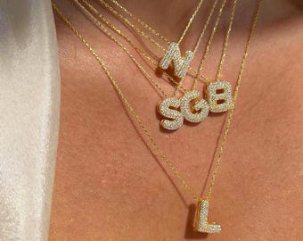 May include: A set of five gold necklaces with diamond-encrusted initial pendants. The initials are N, S, G, B, and L.