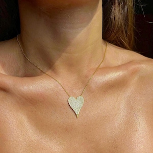 May include: A gold necklace with a large, heart-shaped pendant covered in small, clear stones.