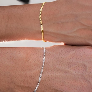 Pu&ograve; includere: Due braccialetti a catena, uno dorato e uno argentato, sul polso di una persona.