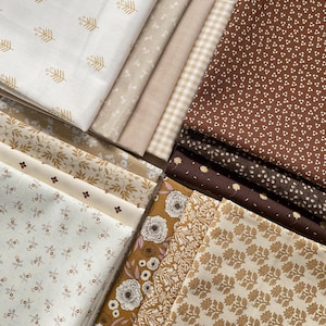 May include: A collection of fabric swatches in various neutral tones, including cream, beige, and brown. The fabrics feature floral, leaf, and gingham patterns. Some fabrics have gold accents. Ideal for quilting or other craft projects.