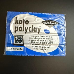 May include: A blue package of Kato Polyclay, a polymer clay product. The package includes the brand name, oven temperature instructions, and the weight of the clay, 12.5 oz (354g).