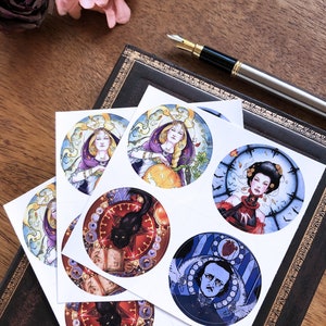 May include: Six round stickers featuring illustrations of a woman with a crown, a woman with a pumpkin, a woman with a clock, a black cat with a book, a man with a heart, and a black cat with a book. The stickers are on a white background.