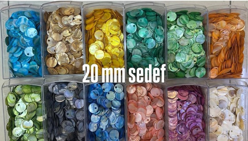 May include: A collection of 20 mm mother of pearl shell discs organized in twelve clear plastic bins. The circular discs feature a single hole and are sorted by color, including blue, gold, yellow, teal, green, orange, olive, grey, pink, purple, and white.