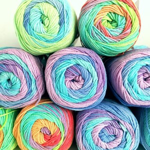 May include: A collection of colorful yarn skeins in a variety of rainbow hues. The yarn is arranged in a stack, with each skein displaying a gradient of colors, including blues, greens, purples, and oranges. The yarn is tightly wound, suggesting a high-quality material.