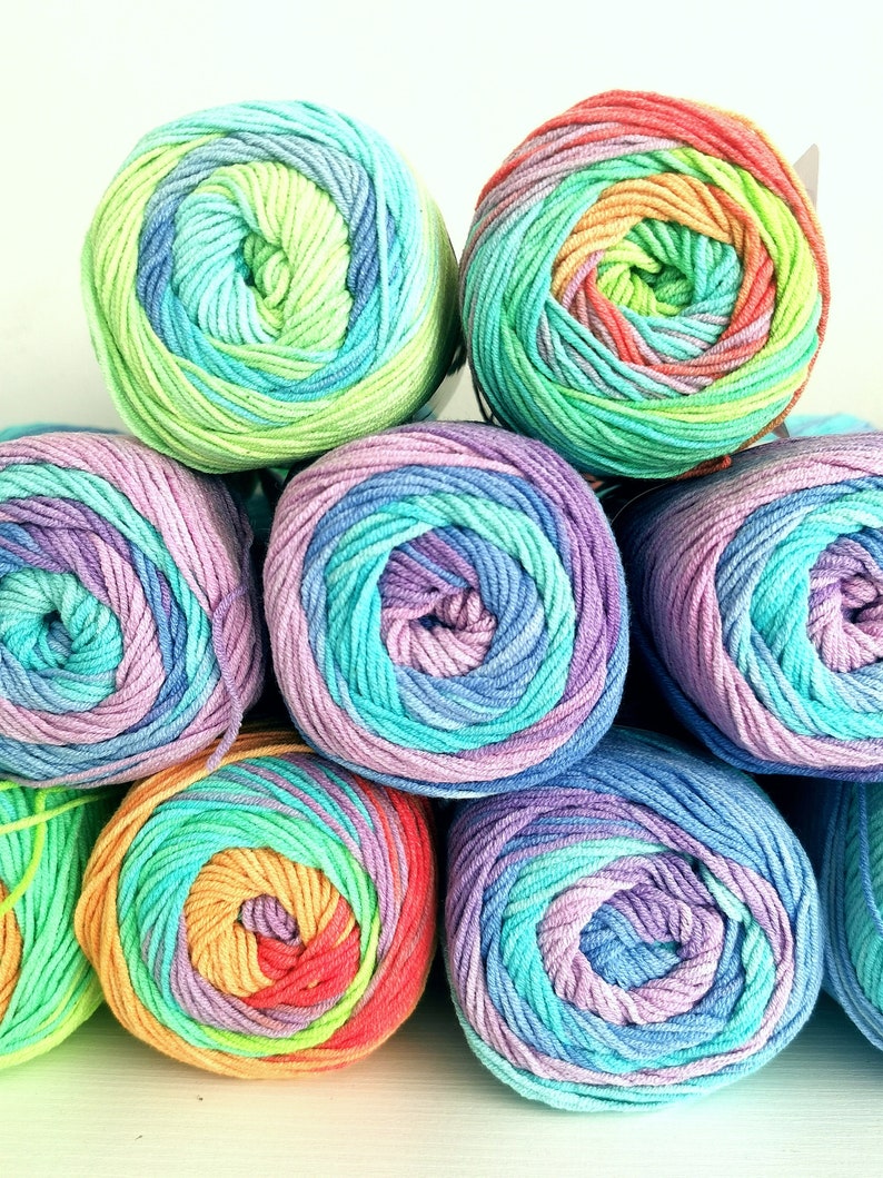 May include: A collection of colorful yarn skeins in a variety of rainbow hues. The yarn is arranged in a stack, with each skein displaying a gradient of colors, including blues, greens, purples, and oranges. The yarn is tightly wound, suggesting a high-quality material.