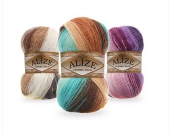 Puede incluir: Tres ovillos de lana en diferentes combinaciones de colores. Cada ovillo tiene una etiqueta que dice "Alize Angora Gold".