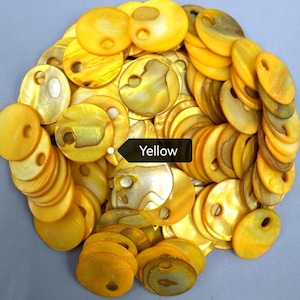 May include: A collection of circular yellow shell buttons, each featuring a single off-center hole. The buttons exhibit a natural, iridescent, and glossy finish with varying shades of golden yellow and subtle pearlescent textures throughout.