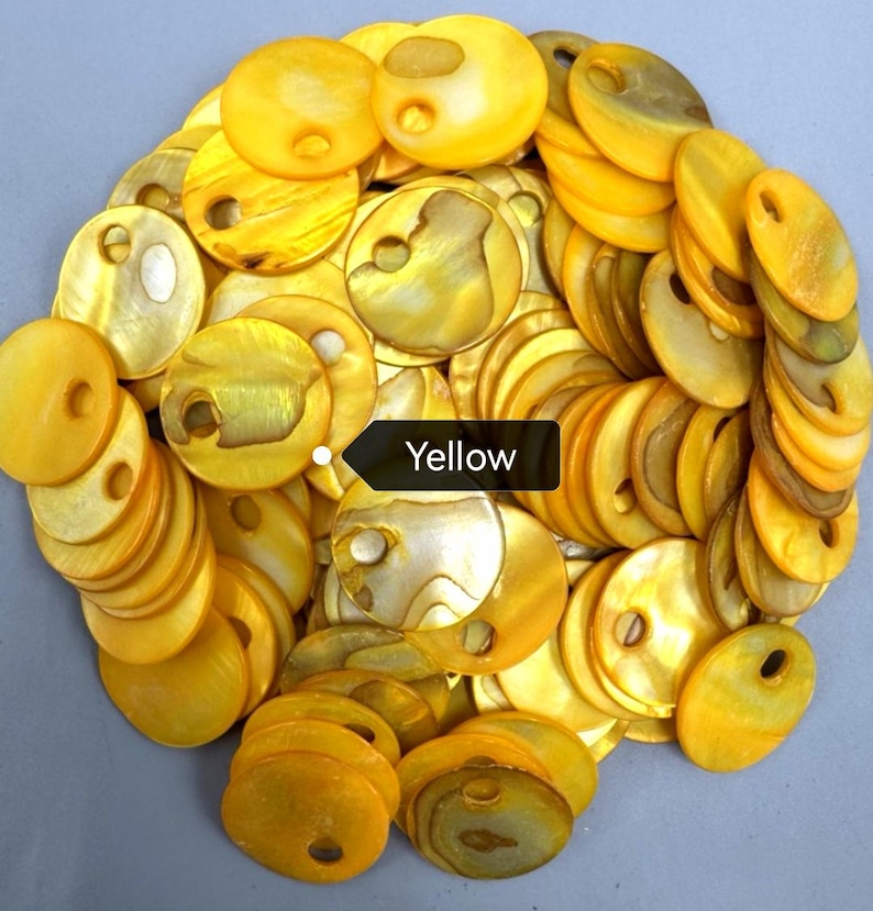 May include: A collection of circular yellow shell buttons, each featuring a single off-center hole. The buttons exhibit a natural, iridescent, and glossy finish with varying shades of golden yellow and subtle pearlescent textures throughout.