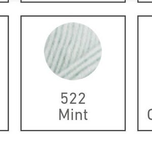 May include: Three balls of yarn in different colours: a light pink ball labelled "505 K&uuml;l&uuml; L&uuml; Lila", a light blue ball labelled "522 Mint", and a grey ball labelled "684 Optik Melanj".