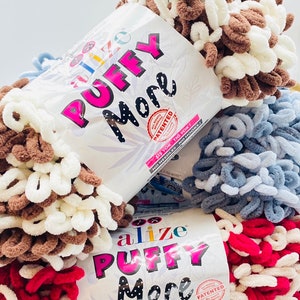 May include: Three balls of Alize Puffy More yarn in brown and white, blue and white, and red and white. The yarn has a bulky, chenille-like texture. The packaging says "All Rights Reserved Patented" and "Sis Yok - Tig Yok! No Needles - No Hooks!"
