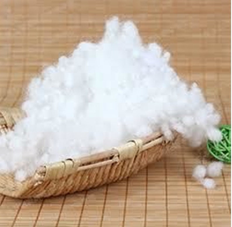 Pode incluir: Um material branco, macio e semelhante ao algod&atilde;o que preenche uma cesta tecida. A cesta &eacute; feita de materiais naturais e tem uma cor castanho claro.
