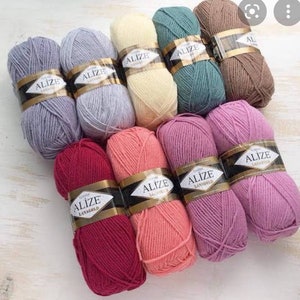 May include: A collection of ten balls of yarn in various colours, including purple, grey, beige, green, brown, red, pink, and light pink. Each ball has a label that reads "Alize Classic LanaGold".