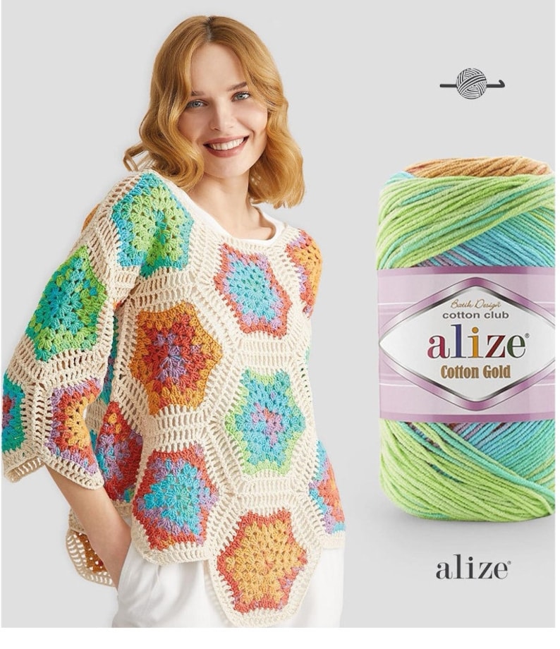 May include: A cream-colored crochet top with colorful hexagon patterns. The top has long sleeves and a round neckline. A skein of Alize Cotton Gold yarn in shades of green, blue, and orange is next to the top.