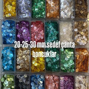 May include: A collection of round, flat mother-of-pearl shell discs in various colors, organized in clear plastic containers. The discs feature a single hole and range in size from 20 mm to 30 mm, labeled as 20-25-30 mm sedef &ccedil;anta boncuklar.