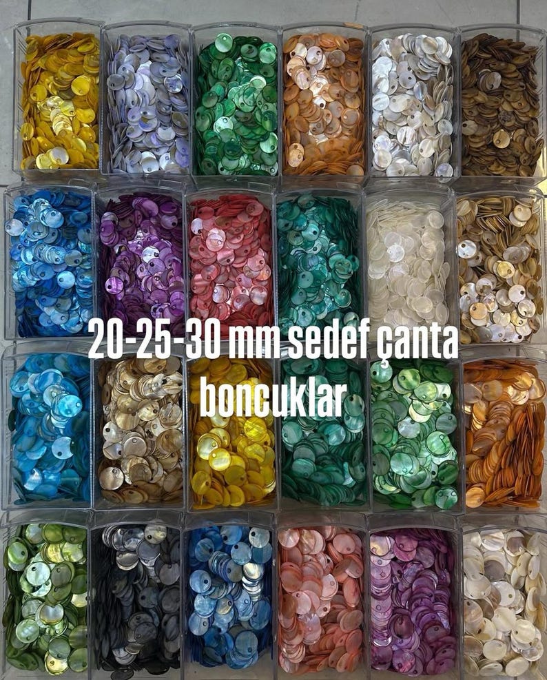 May include: A collection of round, flat mother-of-pearl shell discs in various colors, organized in clear plastic containers. The discs feature a single hole and range in size from 20 mm to 30 mm, labeled as 20-25-30 mm sedef &ccedil;anta boncuklar.