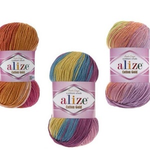 May include: Three skeins of Alize Cotton Gold yarn in various color combinations. The yarn is wrapped with a pink label that has the brand name and product information. The colors include orange, yellow, pink, blue, and purple.