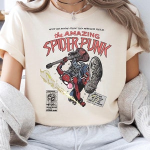 May include: A white t-shirt with a comic book style graphic of a superhero with a guitar. The text on the shirt reads "The Amazing Spider-Punk".