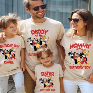 May include: A family of five wearing matching beige t-shirts with a Mickey Mouse racing car graphic. The shirts read "Daddy of the Birthday Boy", "Mommy of the Birthday Boy", "Birthday Boy", and "Sister of the Birthday Boy".