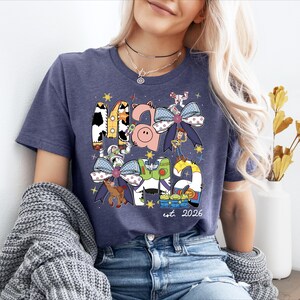 A woman wearing a blue t-shirt with a graphic design featuring various cartoon characters and a small pig.