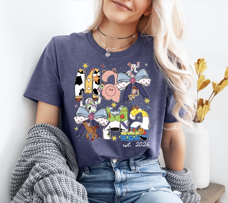 A woman wearing a blue t-shirt with a graphic design featuring various cartoon characters and a small pig.