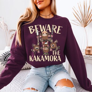 a woman sitting on a bed wearing a purple sweater