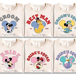 Può includere: Sei magliette color crema con grafiche a tema Disney. Le magliette presentano Topolino e Minnie, Pluto e Paperina, con testi come "Groom", "Best Man", "Bride" e "Bride's Squad". Ogni design include l'anno "2025" e la frase "Happily East After".
