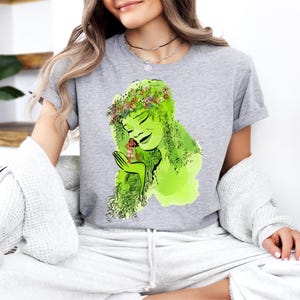 a woman sitting on a couch wearing a t - shirt with a picture of a